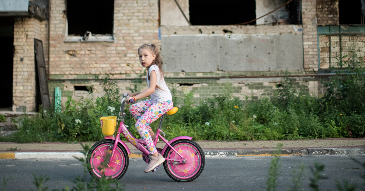 A child on a bicycle rides in front of a damaged building in an Ogilvy-published French Red Cross campaign photograph.