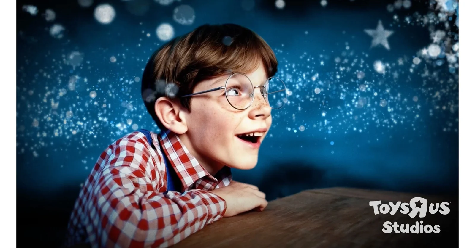 A boy with glasses leans toward a glowing blue dream world; the Toys“R”Us Studios logo remains visible.